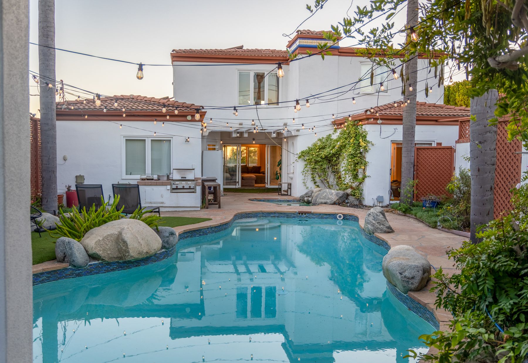 A private courtyard pool enclosed by a home, palms, and climbing greenery.