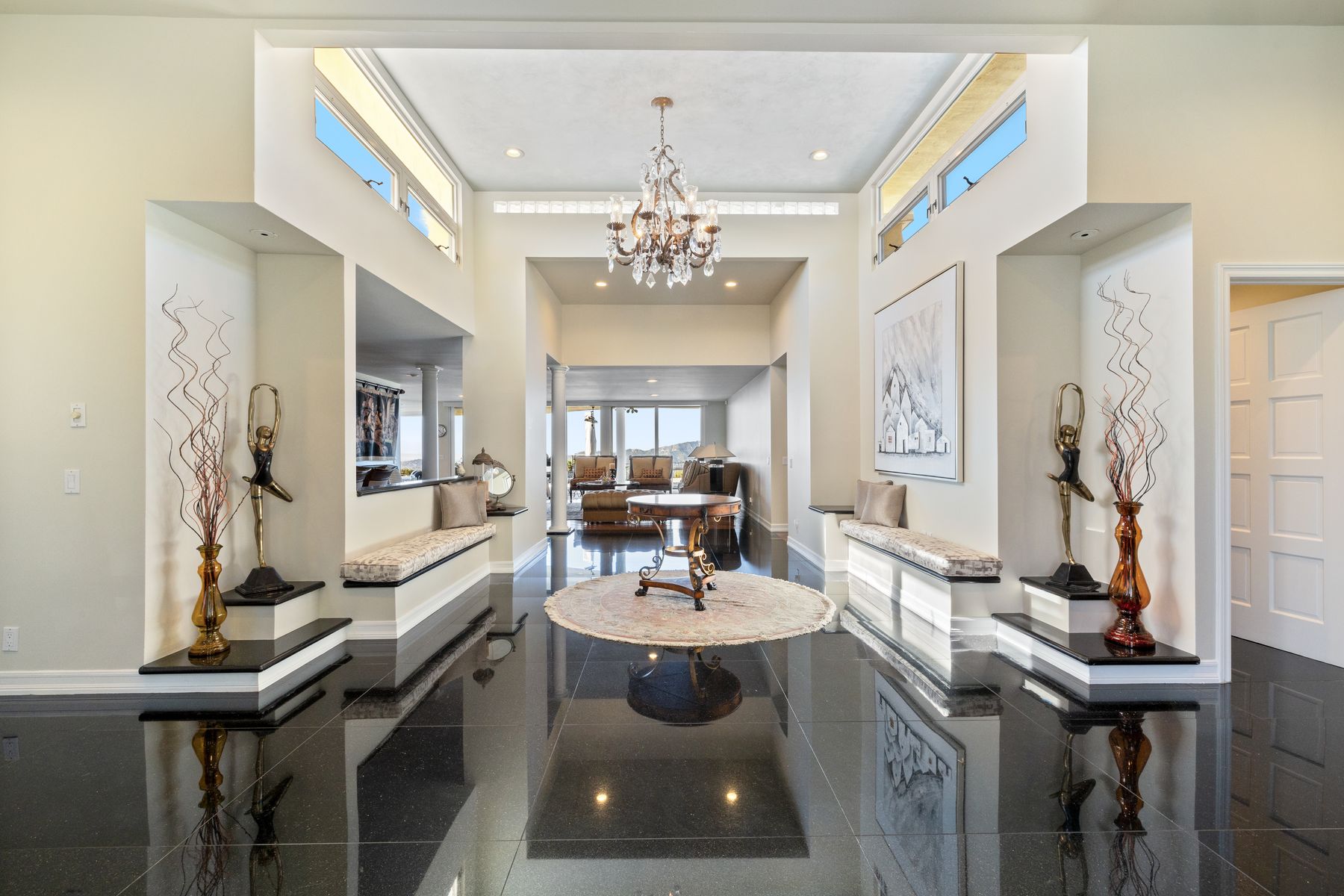A light-filled foyer with a chandelier and polished dark floor.