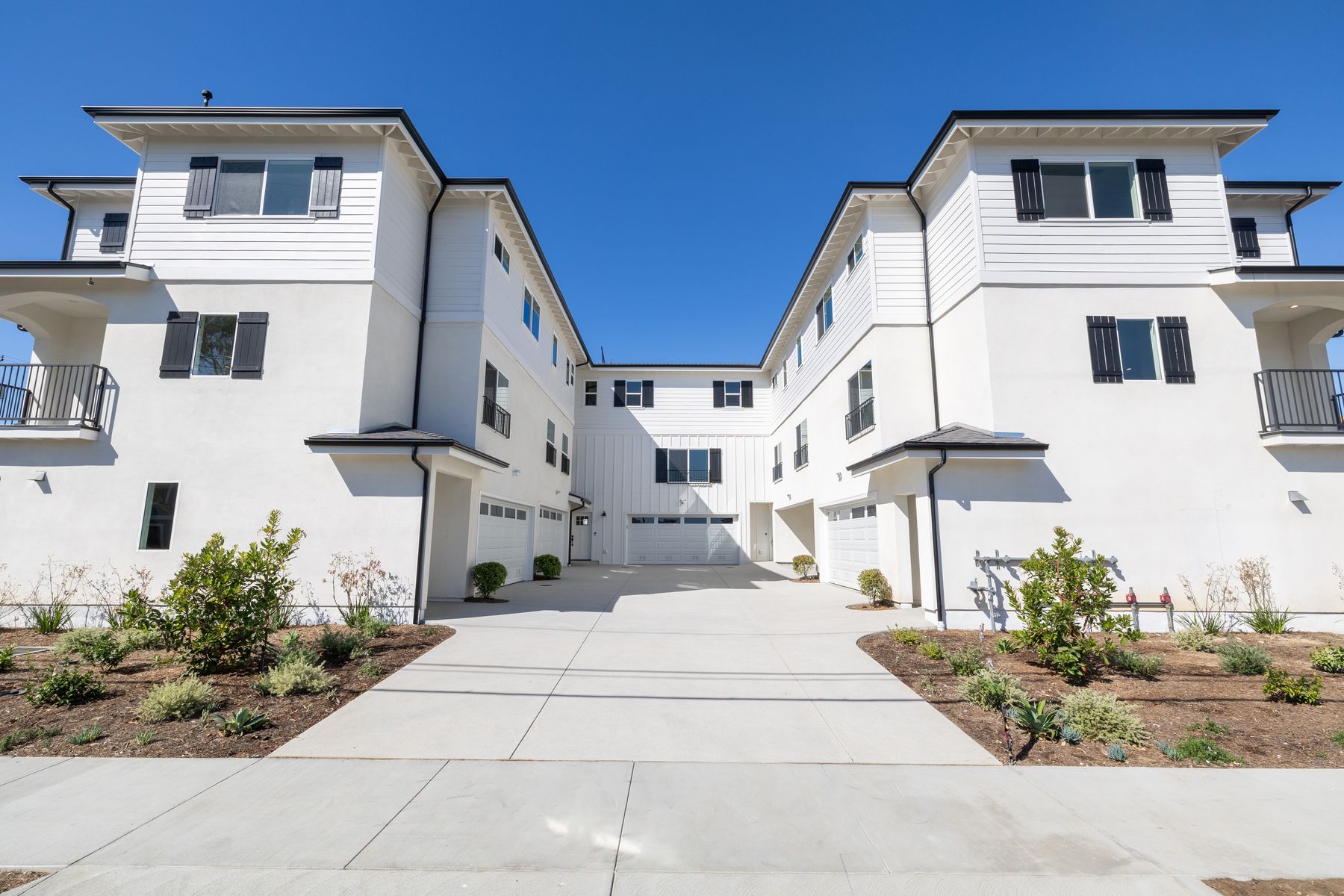 A symmetrical view of a multi-wing residential exterior beneath a clear sky.