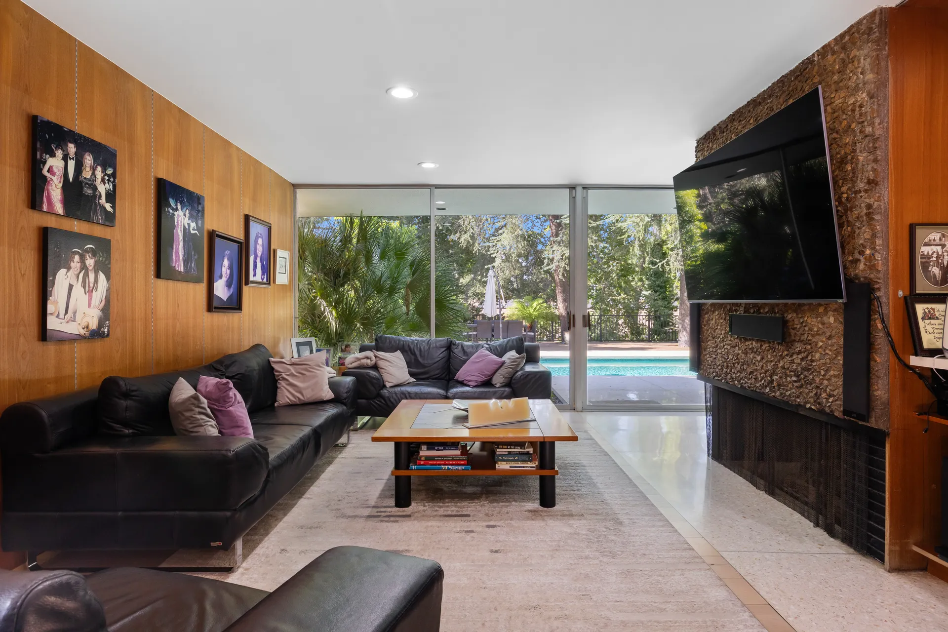 A warm wood living room looking through glass walls toward the swimming pool.