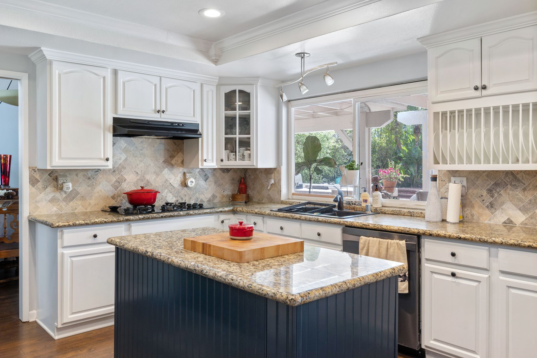 A kitchen with a central island, stone counters, and garden-facing windows.