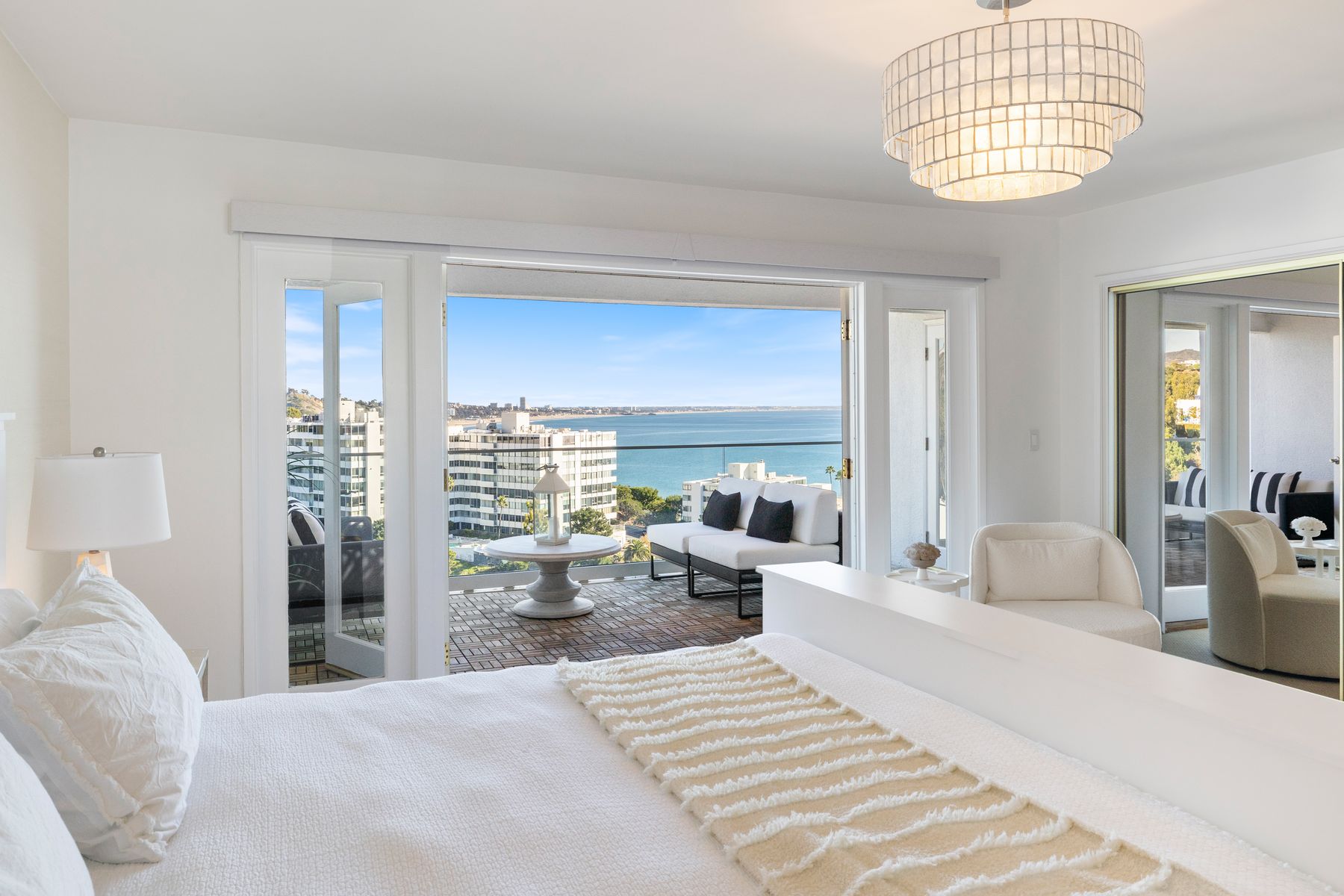 A bedroom opening onto a balcony and expansive coastal view.
